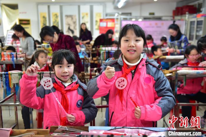 圖為小學生展示繡制好的2022年北京冬奧會吉祥物“冰墩墩”形象。　喻云亮 攝