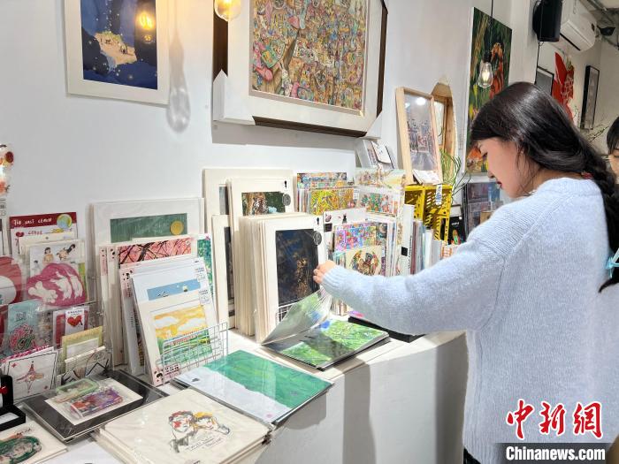 圖為藝術品商店內，顧客挑選插畫作品。　鐘旖 攝