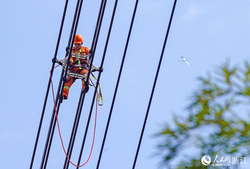 3月11日，在浙江省諸暨市河上鎮(zhèn)，浙江省送變電工程有限公司檢修人員在高空的導(dǎo)線上進(jìn)行線路檢修維護(hù)。人民網(wǎng) 章勇濤攝