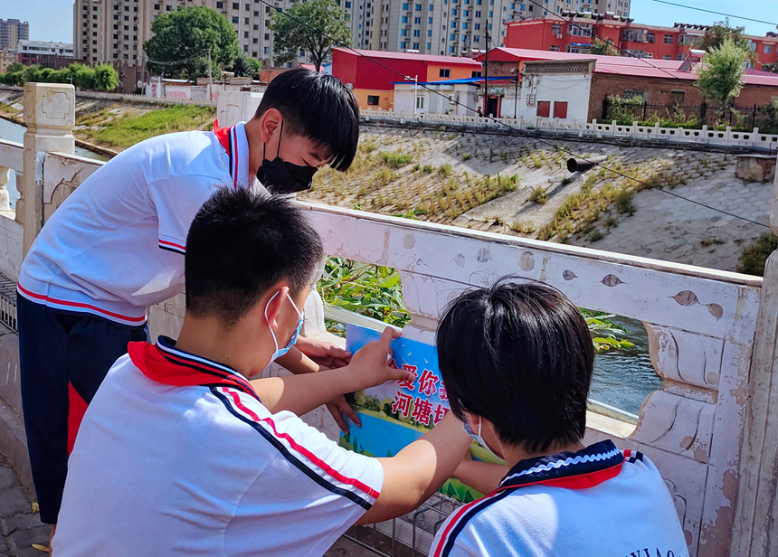 徐水小學(xué)學(xué)雷鋒志愿者在瀑河河邊張貼防溺水警示標(biāo)語(yǔ)。 徐水區(qū)委宣傳部供圖