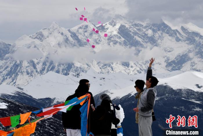 圖為5月14日，游客在西藏林芝色季拉山觀景臺(tái)拋灑“隆達(dá)”(風(fēng)馬旗，藏族民眾的一種祈福方式)?！±盍?攝