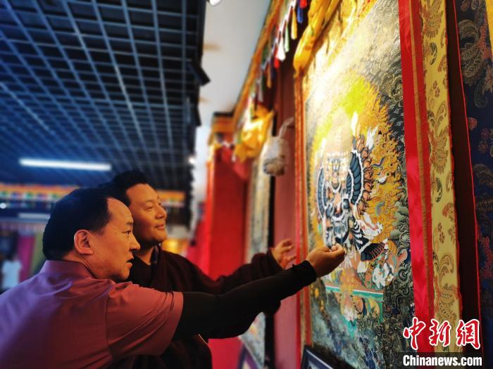 圖為久美尖措展示唐卡作品?！?zhí)砀?攝
