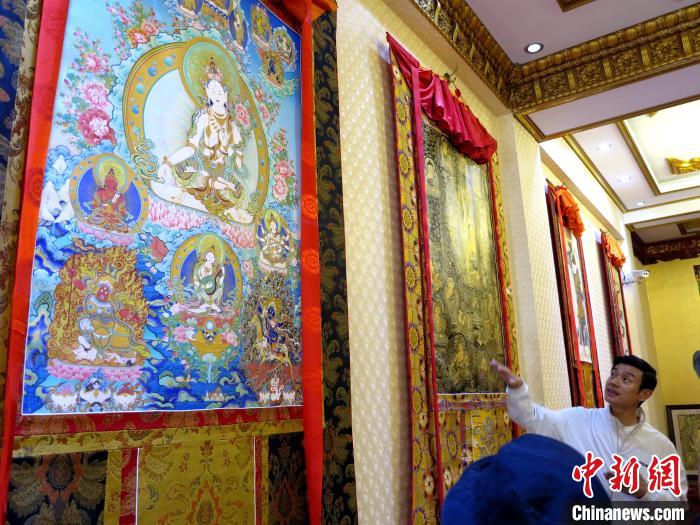圖為完德尖措展示熱貢龍樹畫苑內(nèi)的唐卡?！?zhí)砀?攝