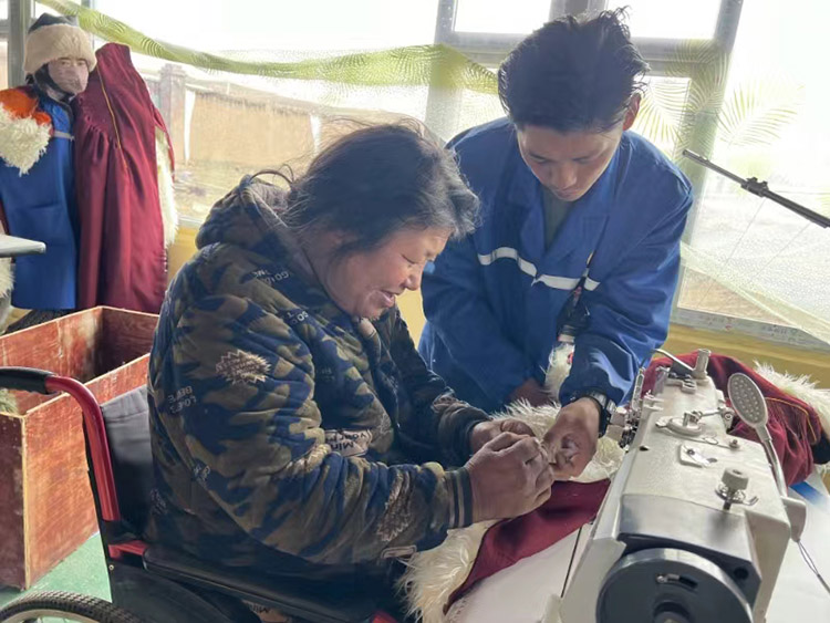 扎西奪爾登幫助殘疾員工裁剪。阿壩州文明辦供圖