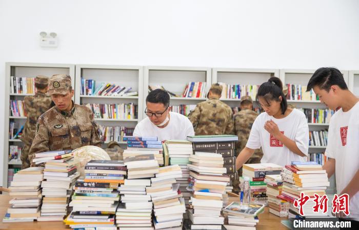 圖為志愿者們和邊防戰(zhàn)士整理圖書?！詵| 攝