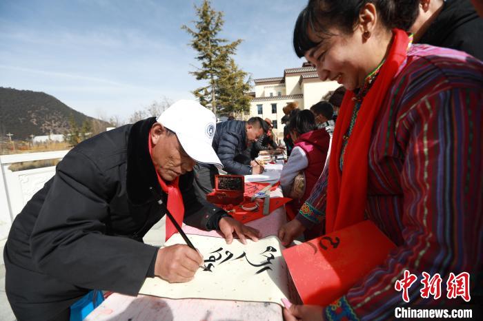 圖為林芝市文聯(lián)書法家協(xié)會(huì)會(huì)員向民眾贈(zèng)送藏文書法作品?！埩?攝